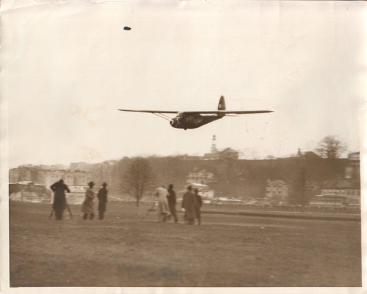 Vintage photograph of a model airplane in flight with spectators on the ground. - Image: Folder21-1